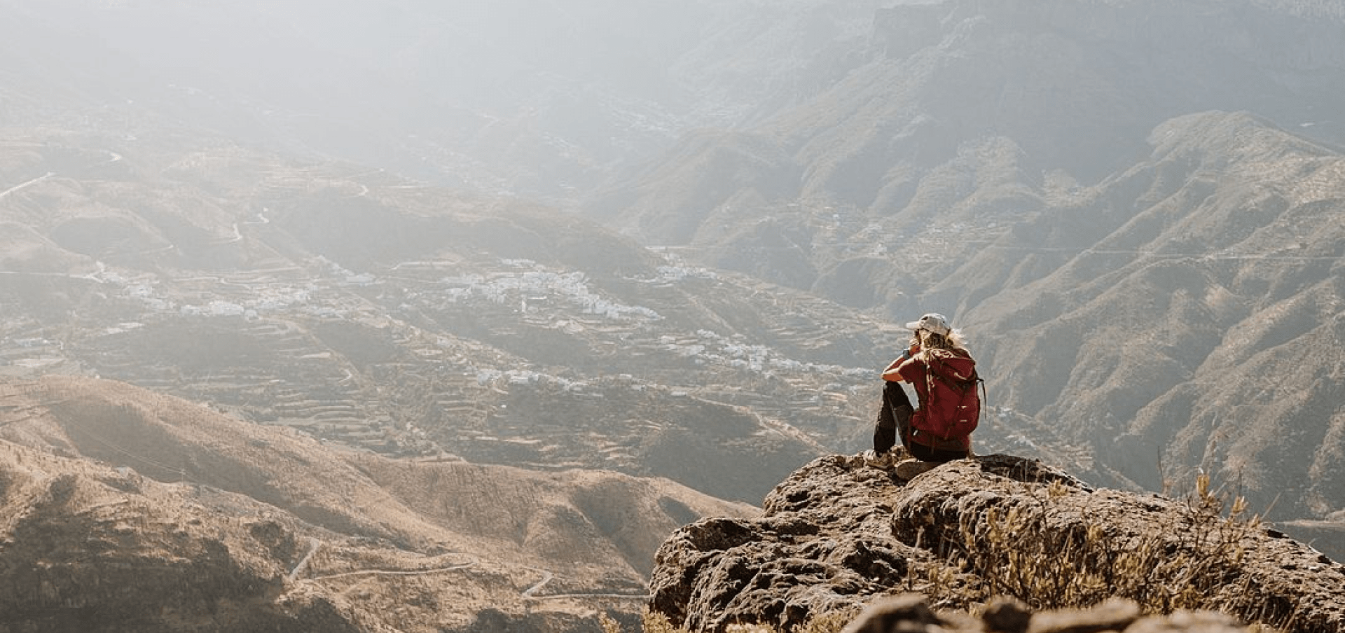 Imagen de una persona sentada en el borde de una montaña