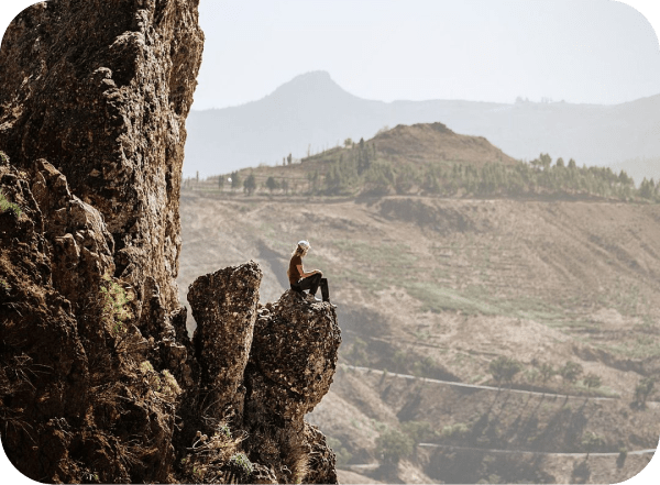 Imagen de una persona sentada en el borde de una montaña