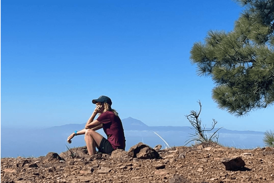 Imagen de una persona sentada descansando en la naturaleza. De fondo se ve el Teide